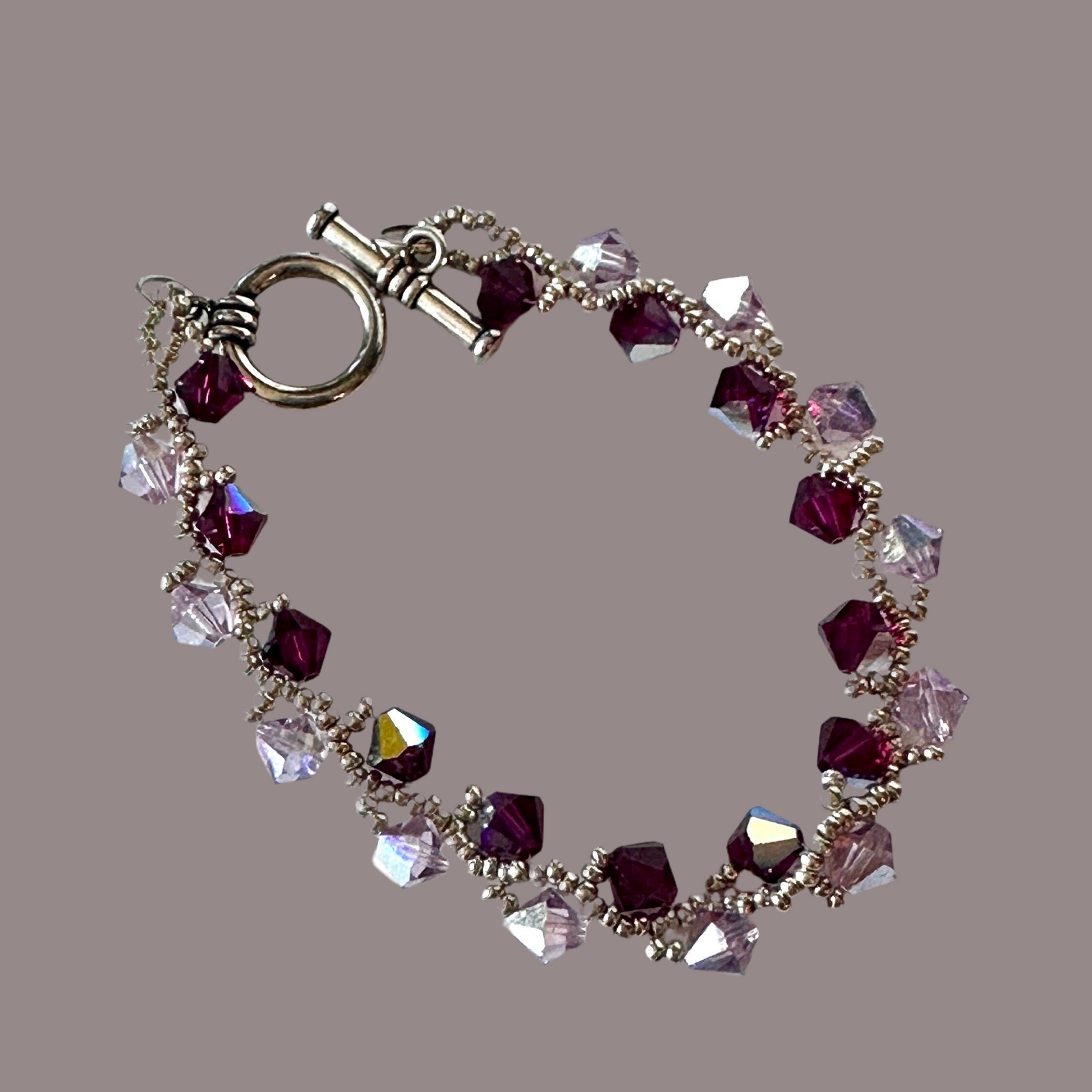 Ruby and light amethyst Swarovski Crystals, hand-woven with silver Miyuki seed beads, and finished with a toggle clasp. - Creations by Rosa