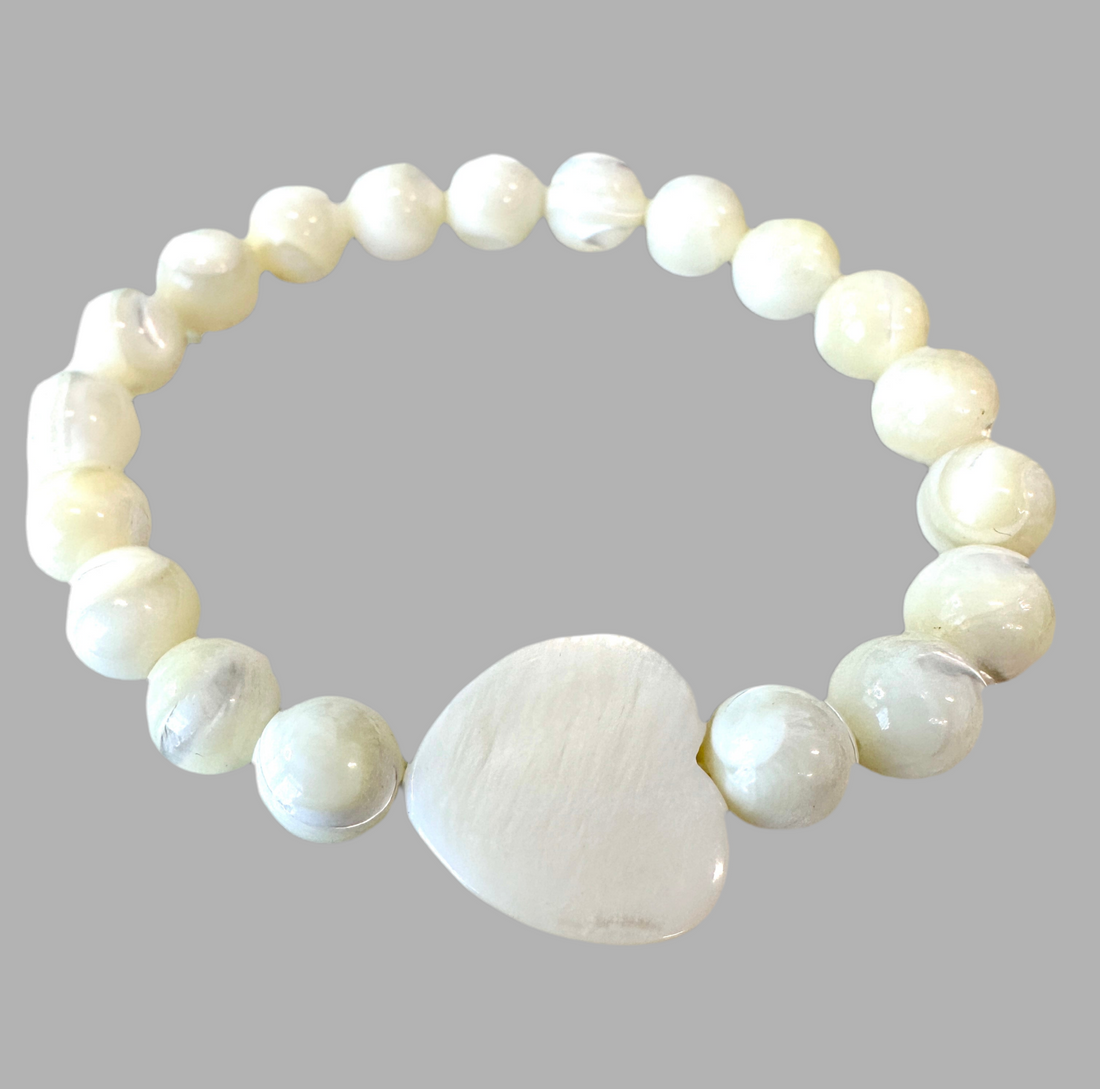 This Mother of Pearl Stretch Bracelet is expertly handmade and features a seashell heart spacer. Ideal for a special gift-giving occasion.