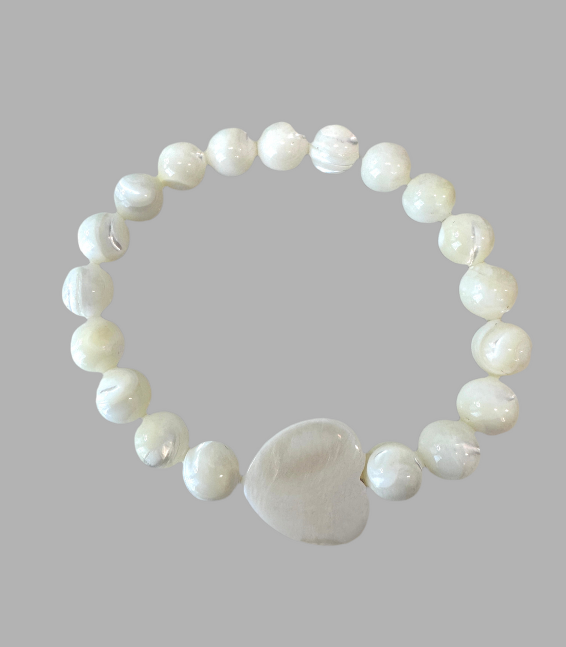 This Mother of Pearl Stretch Bracelet is expertly handmade and features a seashell heart spacer. Ideal for a special gift-giving occasion.