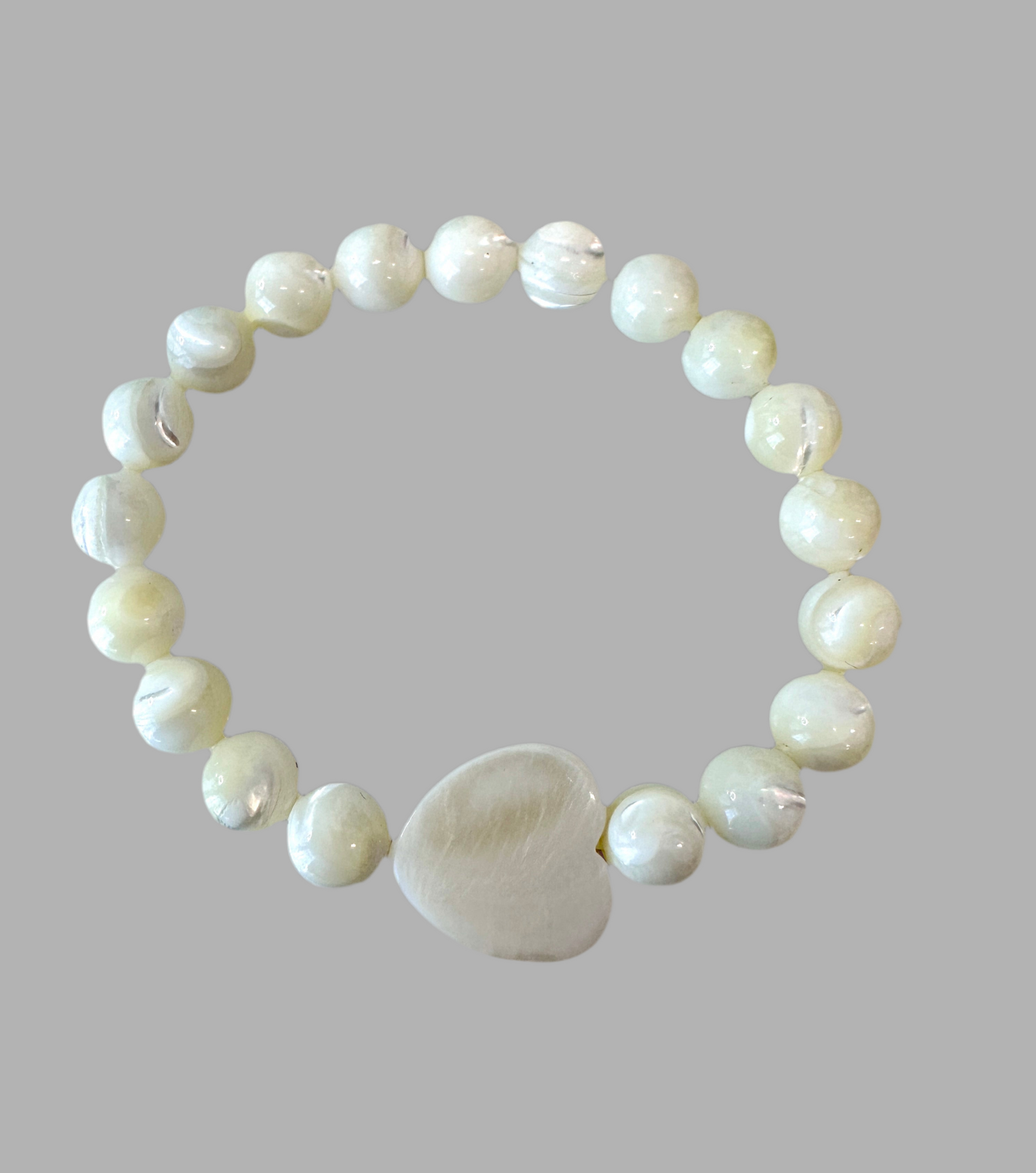 This Mother of Pearl Stretch Bracelet is expertly handmade and features a seashell heart spacer. Ideal for a special gift-giving occasion.