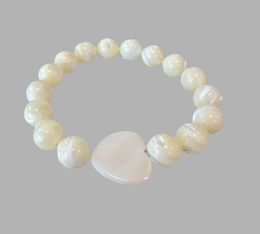 This Mother of Pearl Stretch Bracelet is expertly handmade and features a seashell heart spacer. Ideal for a special gift-giving occasion.